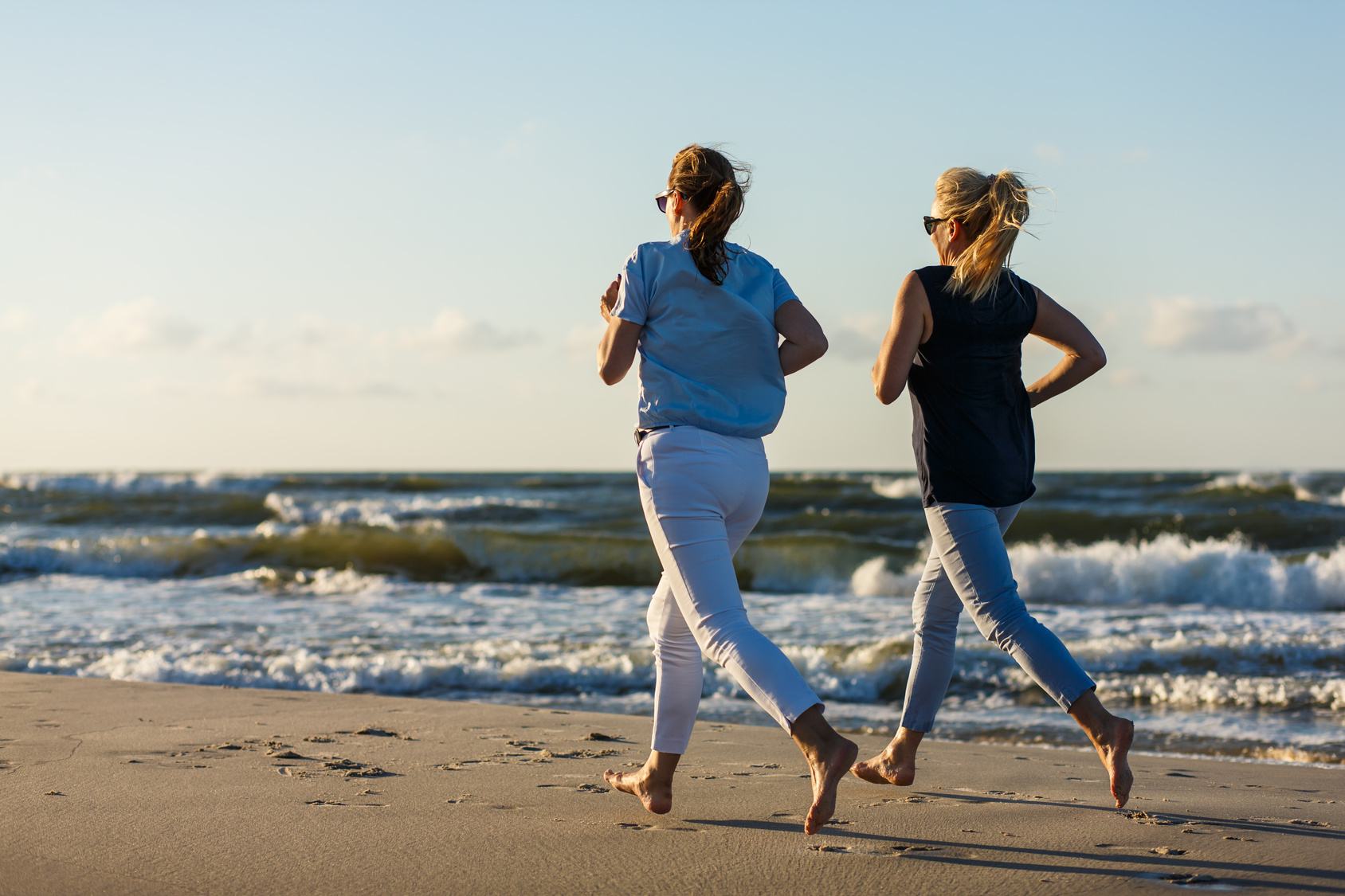 Zwei Frauen joggen am Strand bei schönem Wetter