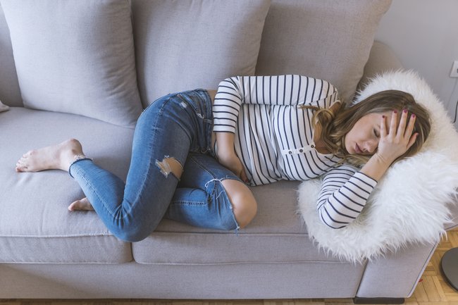 Müde Frau liegt auf dem Sofa